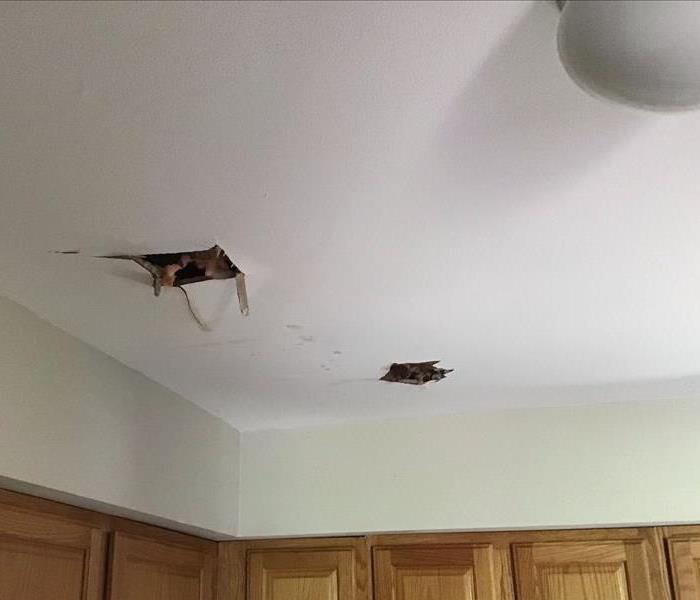 Storm damage to kitchen ceiling from a tree falling on roof during a thunderstorm
