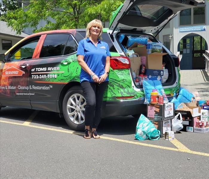 Kathy standing next to SERVPRO of Toms River with car full of food and personal items that were donated