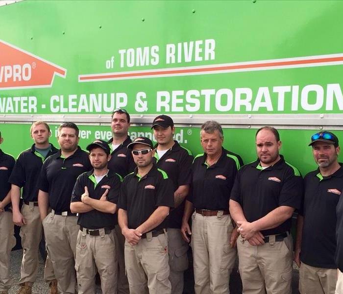 team members standing in front of a green SERVPRO truck